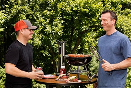 Two men grilling sausages and burgers outdoors.