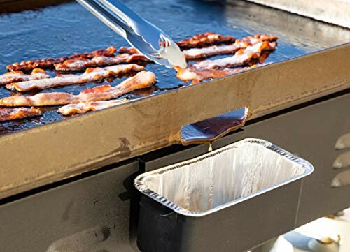 Bacon strips cooking on a griddle with grease dripping into a tray.