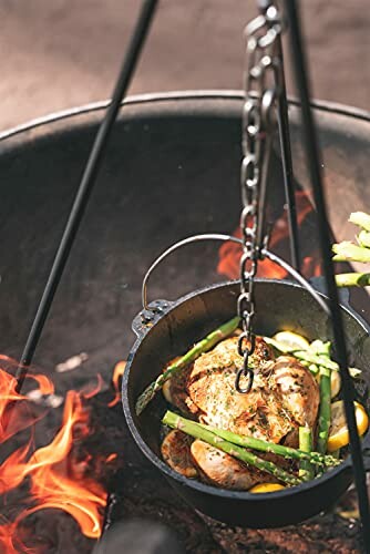 Dutch oven cooking over campfire with chicken and asparagus.