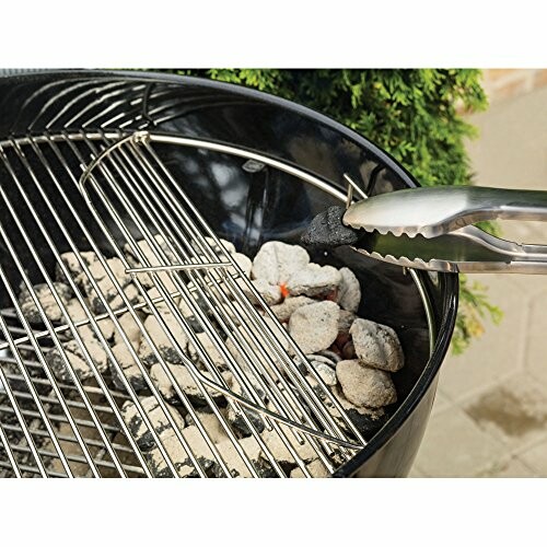 Charcoal grill with tongs adjusting coals.