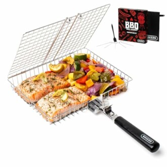 Grill basket with salmon fillets and mixed vegetables beside a BBQ grill book.