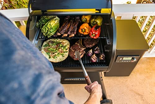 Person grilling vegetables, pizza, and meats on an outdoor grill.