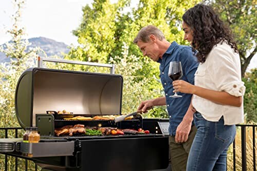 Two people grilling food on an outdoor barbecue.