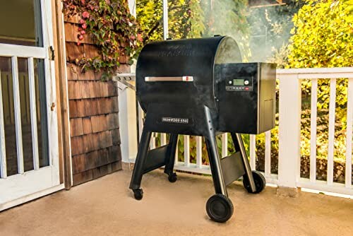 Outdoor pellet grill with smoke on a patio.