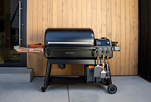 Outdoor pellet grill on a patio with utensils and wood pellets.