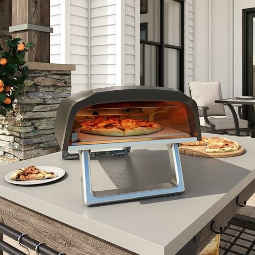 Outdoor pizza oven on patio table with pizzas.