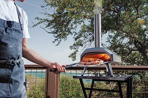 Person using an outdoor pizza oven on a deck.