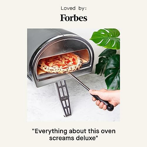 Hand placing pizza in a portable pizza oven.