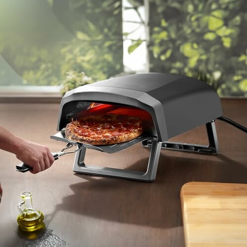 Person using a portable pizza oven to bake a pizza.